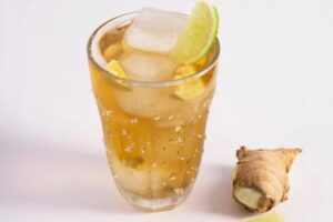 Bicchiere di Ginger Beer con ghiaccio limone e un pezzettino di zenzero