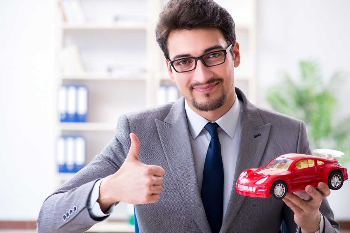 uomo con pollice in su in mano un modellino di auto