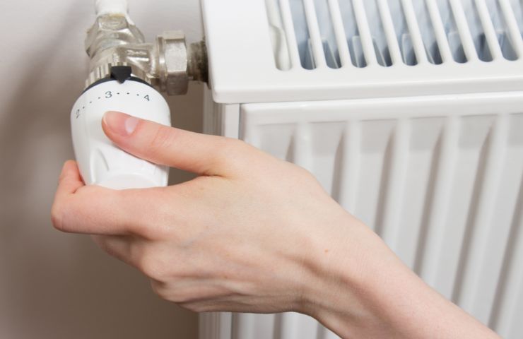 donna che usa valvola termostatica del termosifone