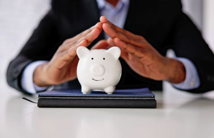 uomo che tiene in mano porcellino a salvadanaio